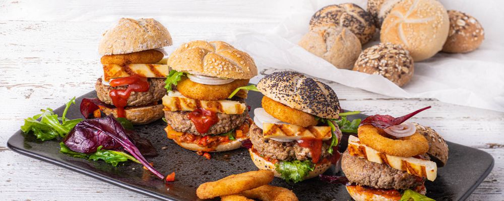 Mini hamburgerek halloumi sajttal, hagymakarikákkal, csípős salsával és salátával